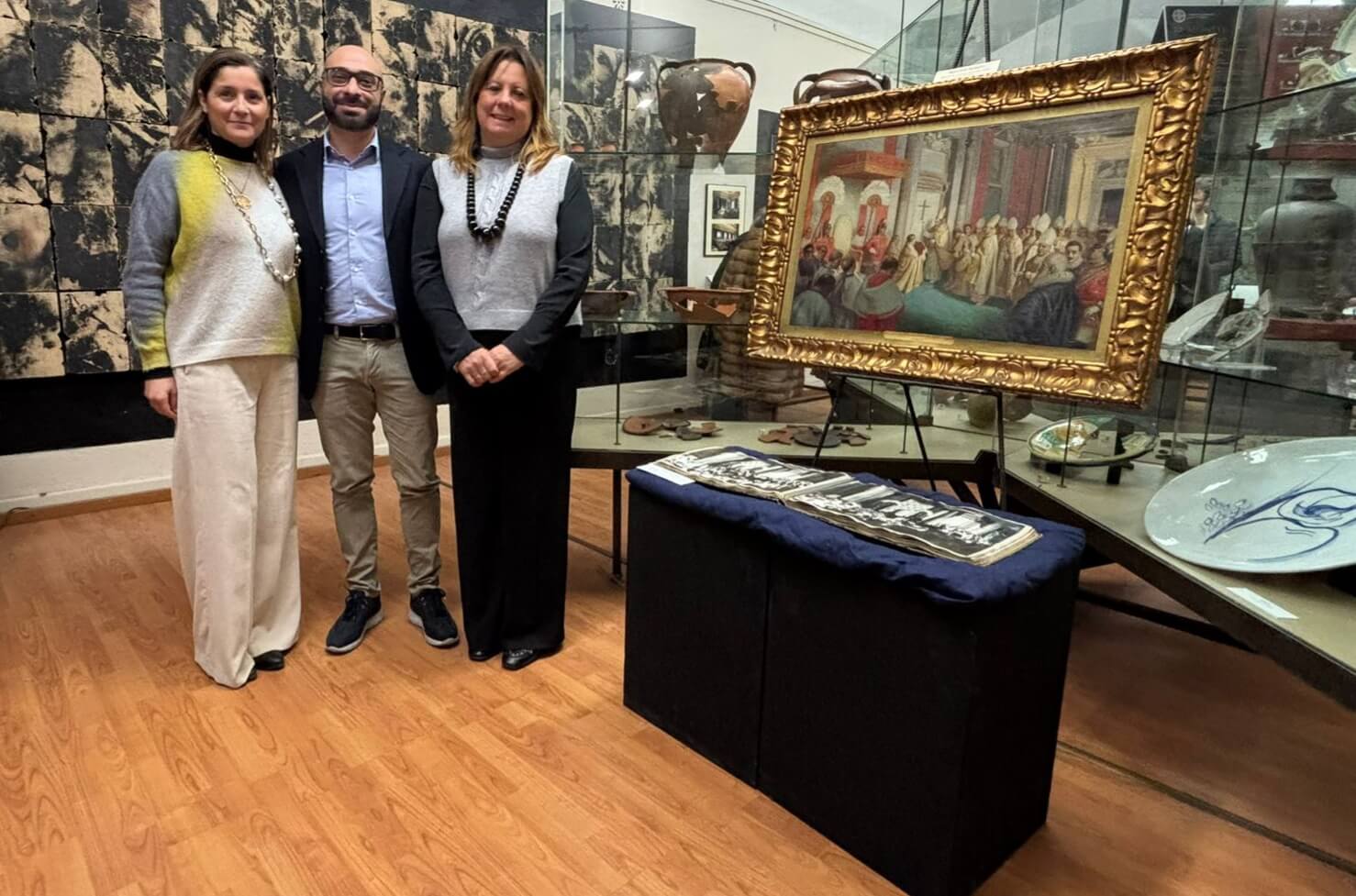 Il giornalista Andrea Cotticelli, la Presidente della STAS Alessandra Sileoni e l’Assessore alla Cultura di Tarquinia Roberta Piroli ritratti vicino l’opera di Francesco Blasetti esposta alla Mostra “100 anni di Giubileo”